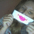 A person holds a white card with a pink lip shape over their mouth in a pixelated image.