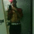 A person in a mirror selfie wearing a red cap, brown jacket, and dark pants, with a white and black striped waistband, holding a phone to take a photo.
