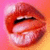 Pixelated close-up of lips with red and pink tones against a gradient background, showing teeth and a black line above the upper lip.