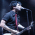 Pixelated image of a musician playing guitar and singing into microphone with 'GREEN DAY' text above red 'american idiot' text on black background.