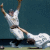 Two baseball players in white uniforms with dark belts and caps, one sliding into base while the other stands ready to catch a ball.