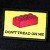 A pixelated static image shows a red oval shape on a yellow background with dark green text below it.