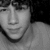 Black-and-white portrait of a person with curly hair, showing three distinct facial expressions