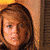 A pixelated image of a person with brown hair wearing a blue bikini top with pink and white patterns, lying on a light-colored surface.