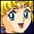 Pixelated anime-style character with blonde hair, blue eyes, and a red gem on forehead, smiling with mouth open, next to stylized text on black background.