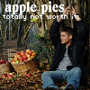 A pixelated image shows a person in a black jacket and blue jeans sitting on the ground with hands behind head, next to baskets of red apples and green foliage.