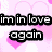 Pixelated text reads 'im in love again' over pink hearts on a light background.