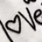 A static image with a white background showing partial black text and a heart symbol, alongside pink pixelated text on a black background.