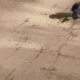 Animated sequence showing a character with spiky black hair and purple eyes performing actions on a sandy terrain background.