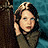 Pixelated static image of a person with dark hair and light skin holding their hand near their face against a blue background.