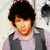 A pixelated image of a person with dark curly hair wearing a light purple shirt and gray vest, next to text reading 'When You Look Me In The Eyes... 444' on a black background.