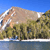Pixelated landscape with a large mountain, green trees, blue sky, and water reflection.