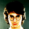 Static pixelated image of a person with dark curly hair, round glasses, and a neutral expression against a muted green background.