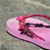 Pixelated pink and red figure on a light pink oval base with dark accents, set against a muted greenish-gray background.