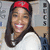 A static pixelated image shows a person with long dark hair wearing a red headband and white top, smiling broadly against a blurred background.