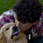 A person in a purple and white plaid shirt holds a light-colored dog against a green grass background, with text overlays changing across frames.
