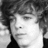 Black-and-white pixelated portrait of a person with curly hair next to blue pixelated text reading "I Love Ryan Sheckler" on a black background.