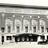 A pixelated grayscale image of a building facade with multiple vertical columns and a horizontal band of text below.