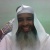 A pixelated static image shows a person wearing a white head covering and light-colored clothing against a muted green background.