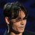 A person with dark hair and a side-swept fringe appears in three views against a blue background, showing subtle shifts in head position.