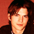 Static pixelated image of a person with brown hair against an orange background, rendered in low-resolution 256x256 pixels.