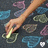 A pixelated image shows a hand holding a glowing object against a dark background with scattered colorful shapes.