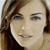 A pixelated close-up of a person with light brown hair, blue eyes, and a neutral expression wearing a dark top against a light background.