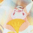 Pixelated static image of a cartoon character with light brown hair, pink cheeks, and white clothing holding a yellow object against a soft pastel background.