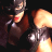 Pixelated static image of a woman with red lips and dark hair in a close-up pose against a black background, wearing a dark outfit with light accents.