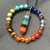 A circular arrangement of multicolored pixelated segments forms a ring on a gray background, with no visible text or distinct objects.