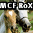 A horse's head in a grassy field with three text overlays: "MCF RoX" at top, "#1barn" on the right, and "Rosie<3" at bottom left.