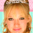 Static 48x48 pixel icon showing a close-up of a person's face with light brown hair, wearing a tiara-like headpiece against a pink and cyan striped background.