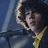 A person with curly brown hair wearing a dark jacket over a yellow shirt appears in three showing head movement