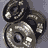 Animated sequence showing a metallic dumbbell rotating through multiple angles against a gray background.