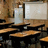 A classroom scene with wooden desks and chairs, a whiteboard, and a water bottle on a desk, with blue text reading "I HATE" and "SCHOOL" overlaid.