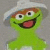 Green puppet-like character with brown eyebrows, large white eyes, and a wide open mouth showing red tongue against gray background.
