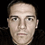 A static image of a man's face with neutral expression, dark hair, and light skin against black background.