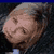 Static pixelated image of a person's face with visible facial features and hair, set against a dark background with blue top border.
