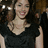 A woman with long brown hair wearing a black sleeveless top smiles at the camera in a of four