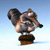 Pixelated figure with large ears and a long snout stands on a brown base against a light blue gradient background.