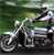 A pixelated static image shows a person riding a motorcycle on a green background with blurred motion effects.