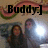 Pixelated image with large black text 'Buddy:]' overlaid on a background featuring two figures and a bright light source.