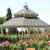 Static pixelated image of a domed building with a chimney, surrounded by greenery and colorful flowers under a light blue sky.