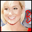 Pixelated close-up of a smiling person with light hair wearing red lipstick and a thin necklace, holding a gray object with red accents.