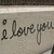 A static image of handwritten text 'i love you' with a small circle above the 'i', displayed on a light gray background with a thin dark border.