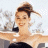 A pixelated image of a person with hair in an updo, wearing dark clothing and white shoulder accents against a light background.