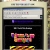Static pixelated image showing a computer screen with dark background displaying colorful abstract shapes and text elements.