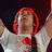 Pixelated image of a person with red hair wearing a white shirt and red tie, arms raised against a dark background.