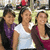 Three people stand side-by-side in a pixelated image; the central figure wears a white sleeveless top, left person purple and black clothing, right person maroon and dark brown attire.