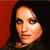 Pixelated close-up of a person with long dark hair against a red and black background, wearing a dark top.